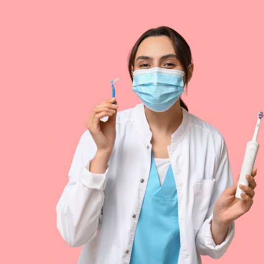Dentist in blue mask holding interproximal and electronic toothbrushes