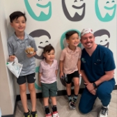 Two pediatric dental team members and young patient smiling together