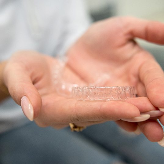Closeup of patient holding clear aligners