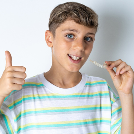 Teenage boy holding an Invisalign aligner in Lake Zurich 