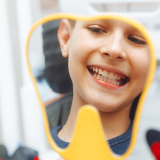 a boy looking in a mirror at the dental office