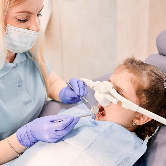 Little girl in dental chair with nitrous oxide mask undergoing oral exam