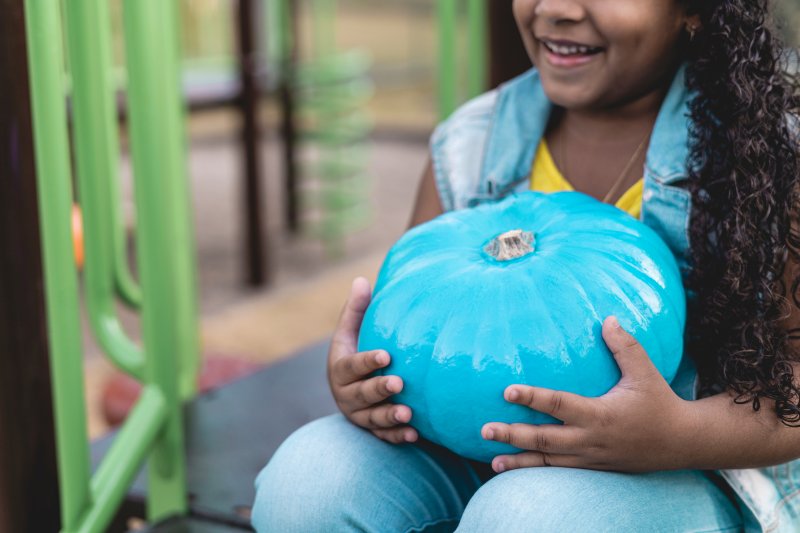 child holding teal pumpkin