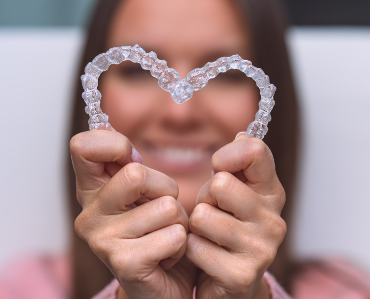 Woman holding Invisalign aligners in a heart shape