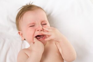 Upset infant with tooth in mouth.